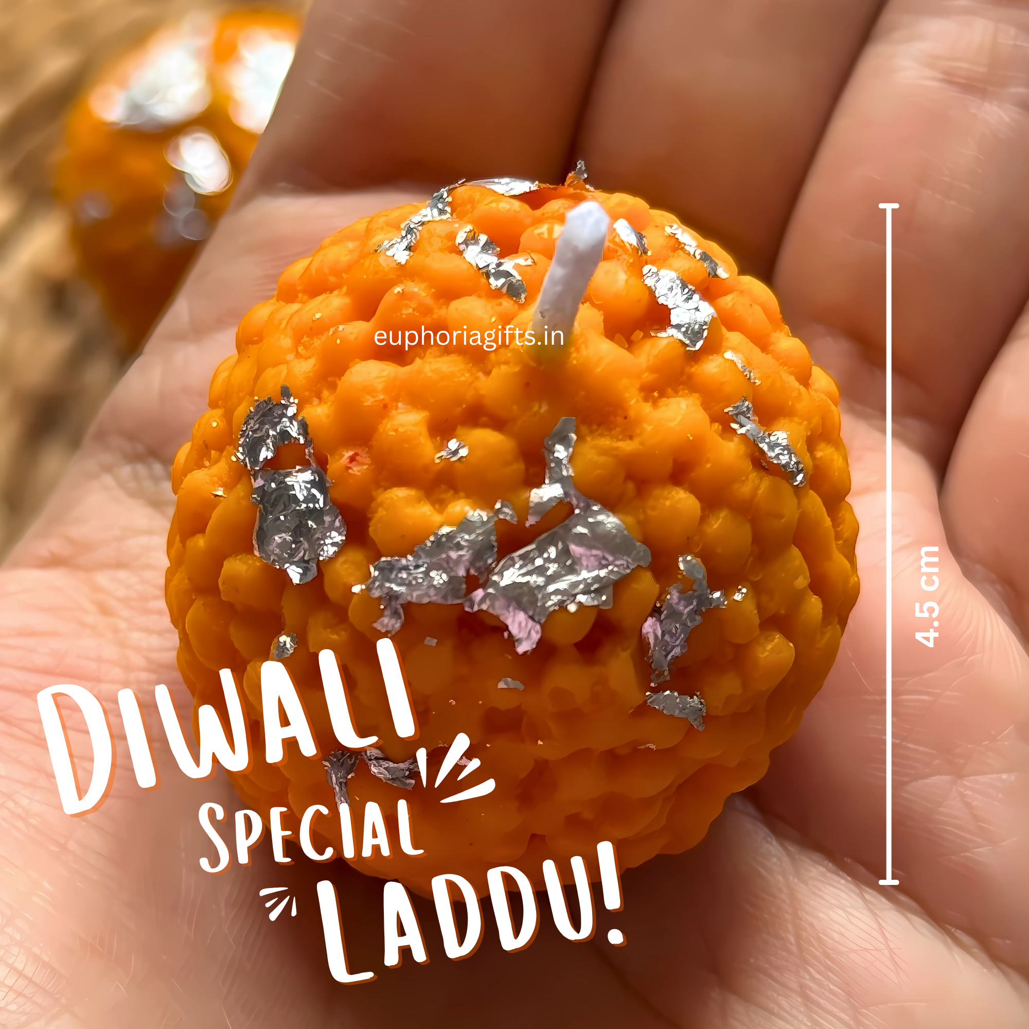 Orange candy shaped like a ball with silver decorations, held in a hand, labeled 'Diwali Special Laddu'. “Handmade mithai candles in gift box for Diwali hampers”