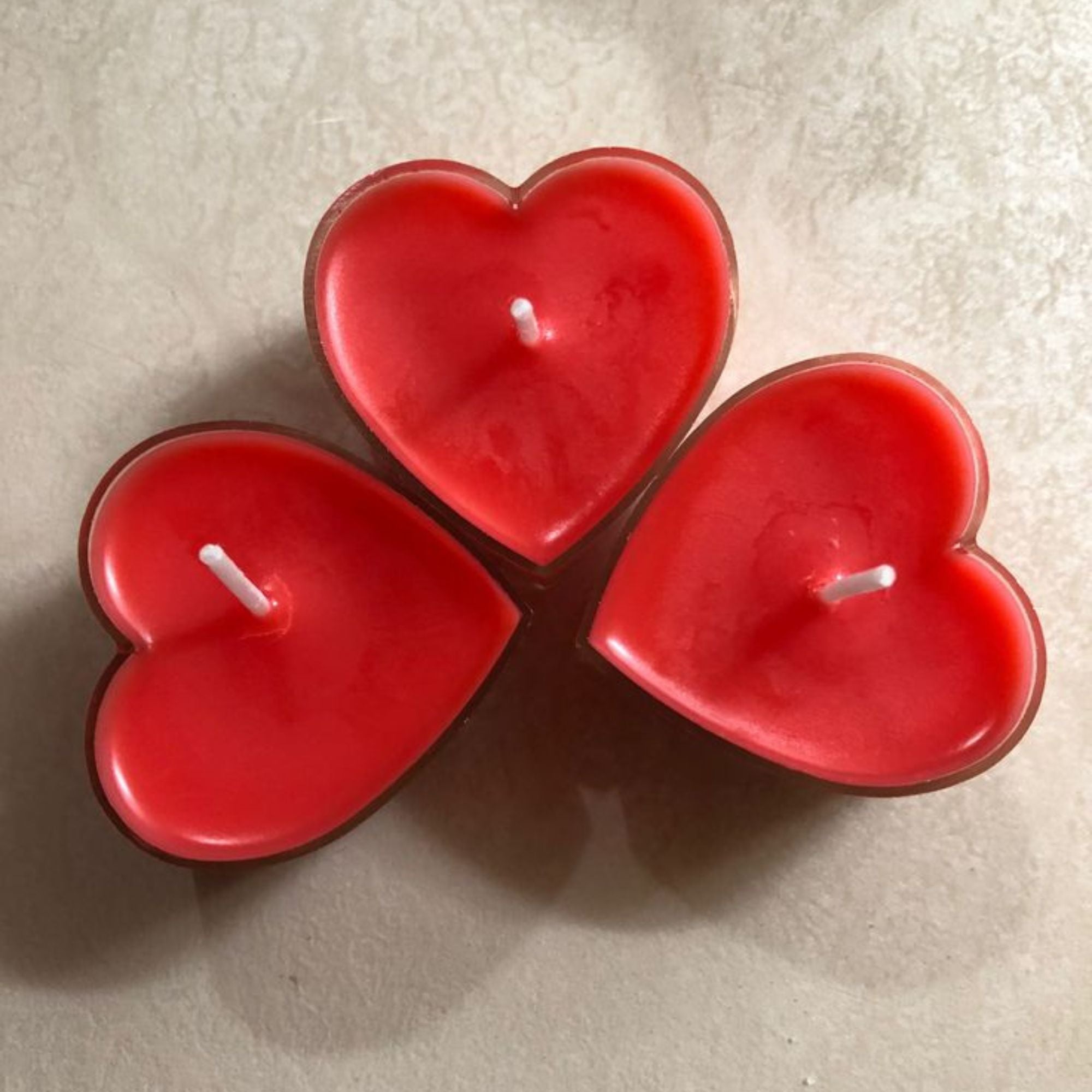 Pink heart-shaped candle with a flame on a white background, featuring the brand 'euphoriagifts.in'.