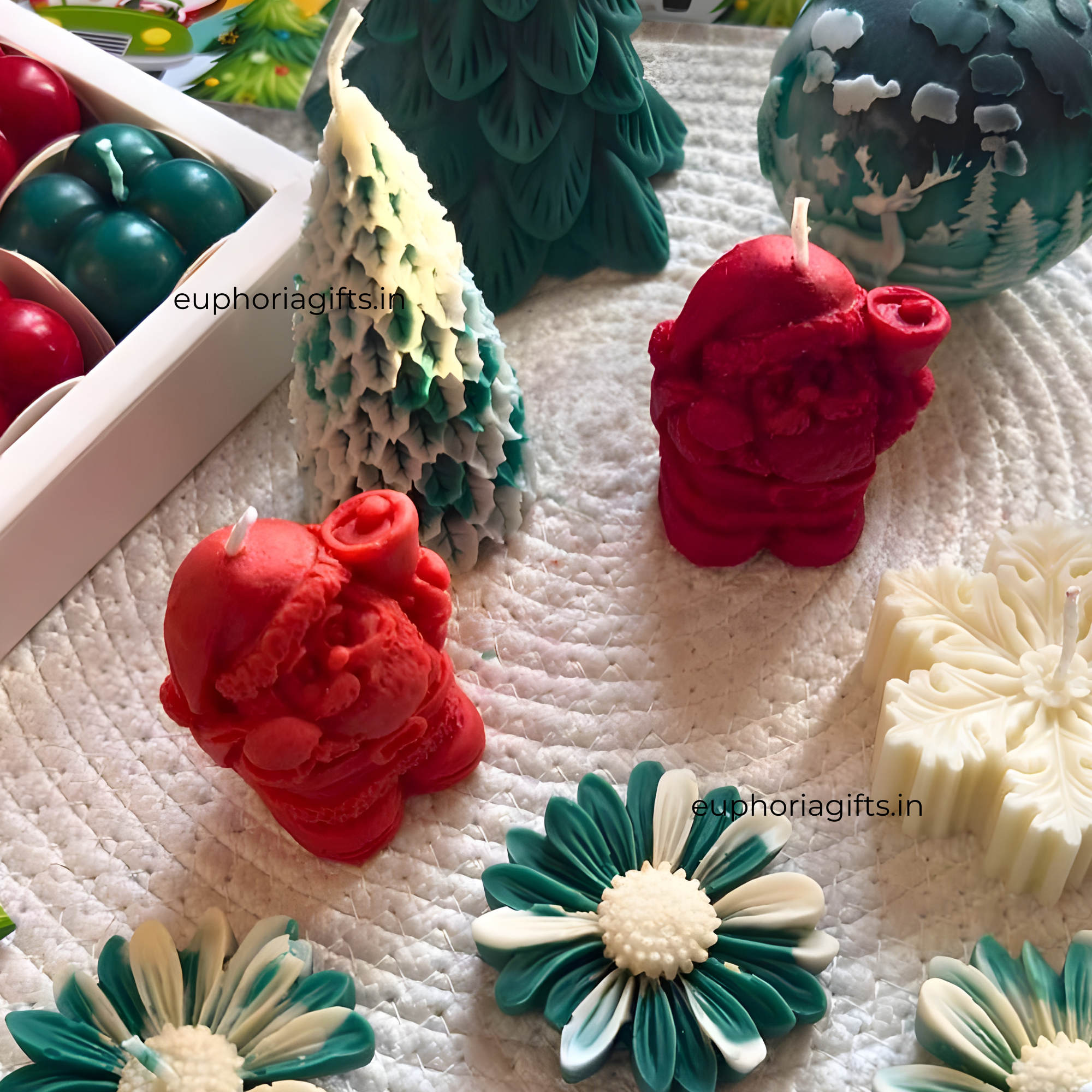 Assorted decorative candles on a textured surface with 'euphoriagifts.in' branding.