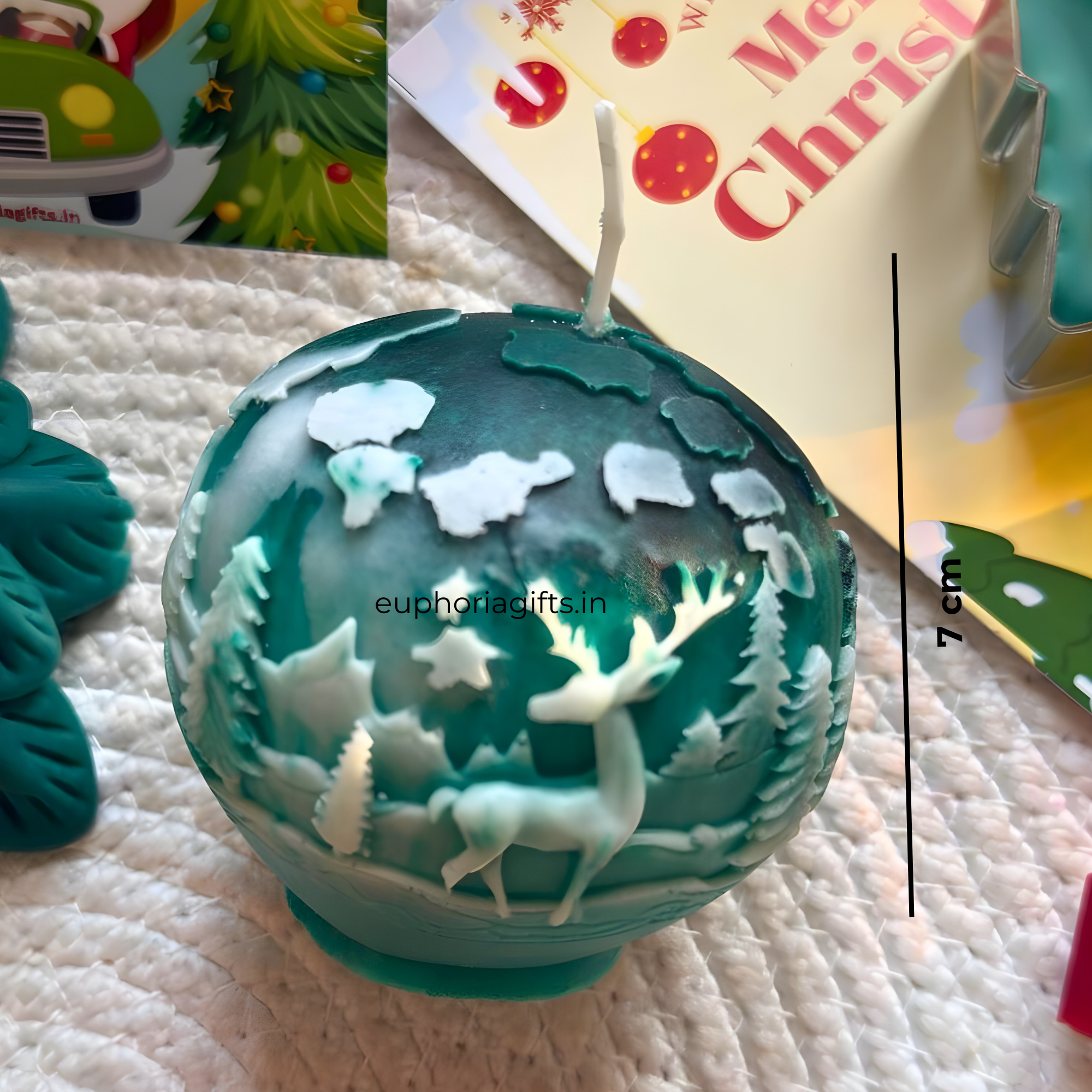 Decorative Christmas ball candle with cut-out designs on a textured  Teal carved Christmas candle holiday décorsurface.