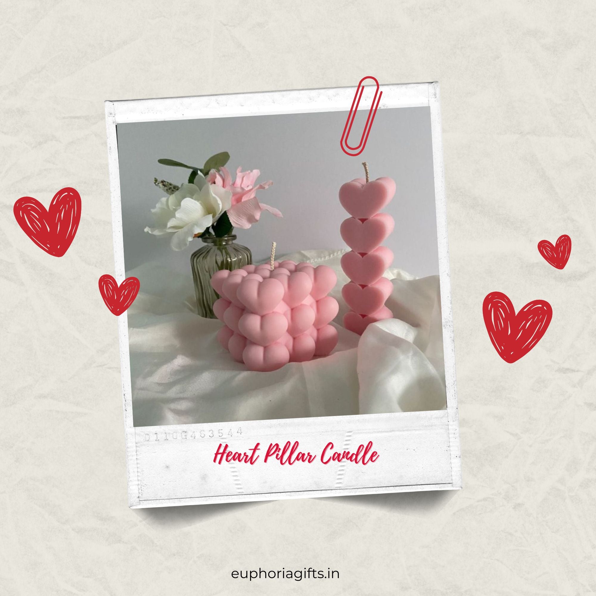 Pink heart pillar and cube candles styled with artificial flowers, captured in a Polaroid frame for a Valentine’s gift aesthetic. Heart-shaped pillar candles with a decorative paper clip on a light background, featuring the brand 'euphoriagifts.in'.