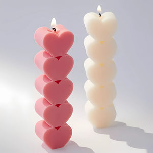 Heart-shaped pillar candles in pink and white, stacked in vertical layers and lit, perfect for romantic and aesthetic home decor.